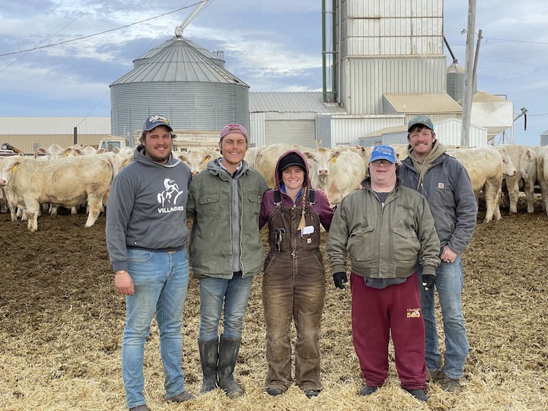 People standing in front of a herd of white cattle on a farm in the US